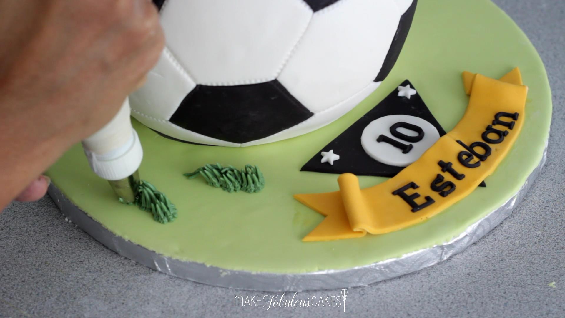 adding grass on the soccer cake board with buttercream