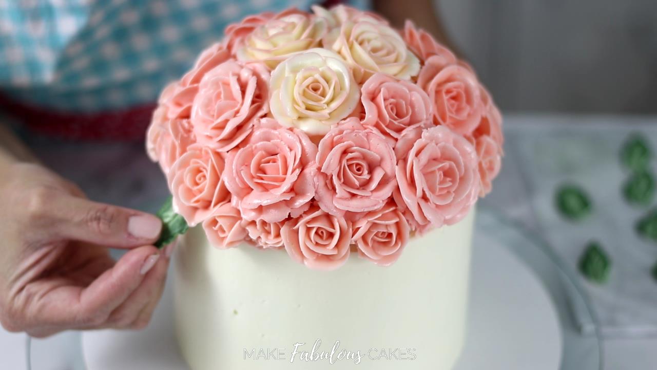 adding leaves to the bouquet of buttercream flowers