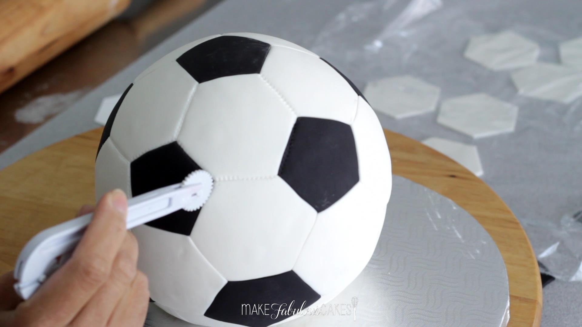 adding the stitch on football cake using a tracing wheel