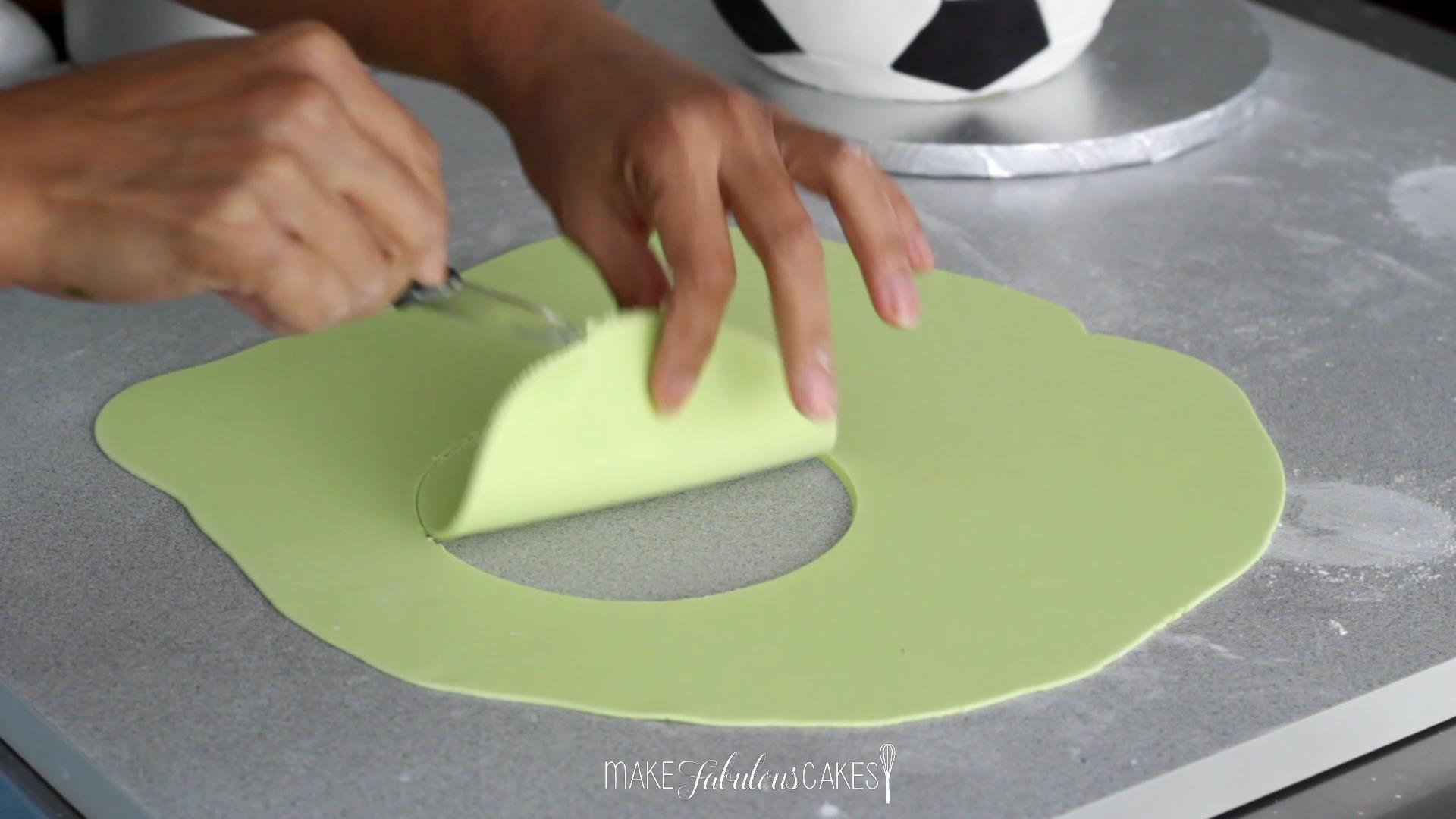covering the soccer cake board with fondant