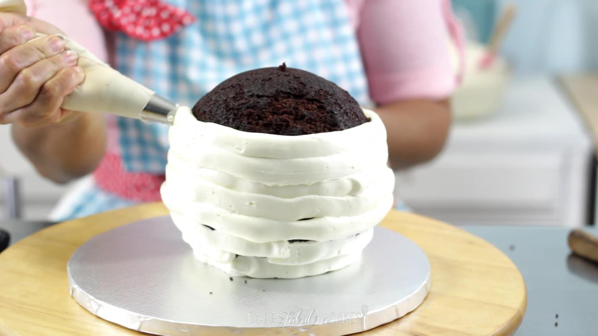 frosting the soccer ball cake using a pastry bag with buttercream