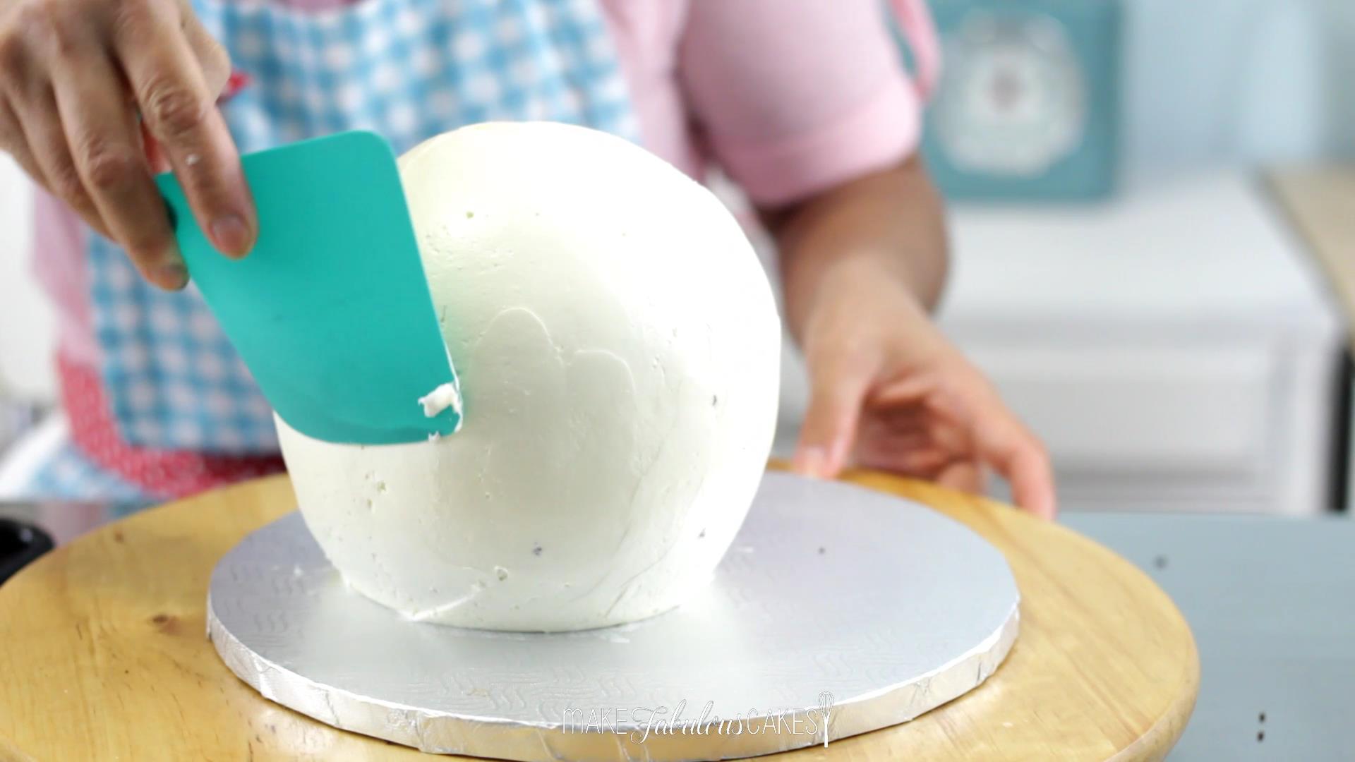 smoothing the ball cake with flexible plastic or acetate