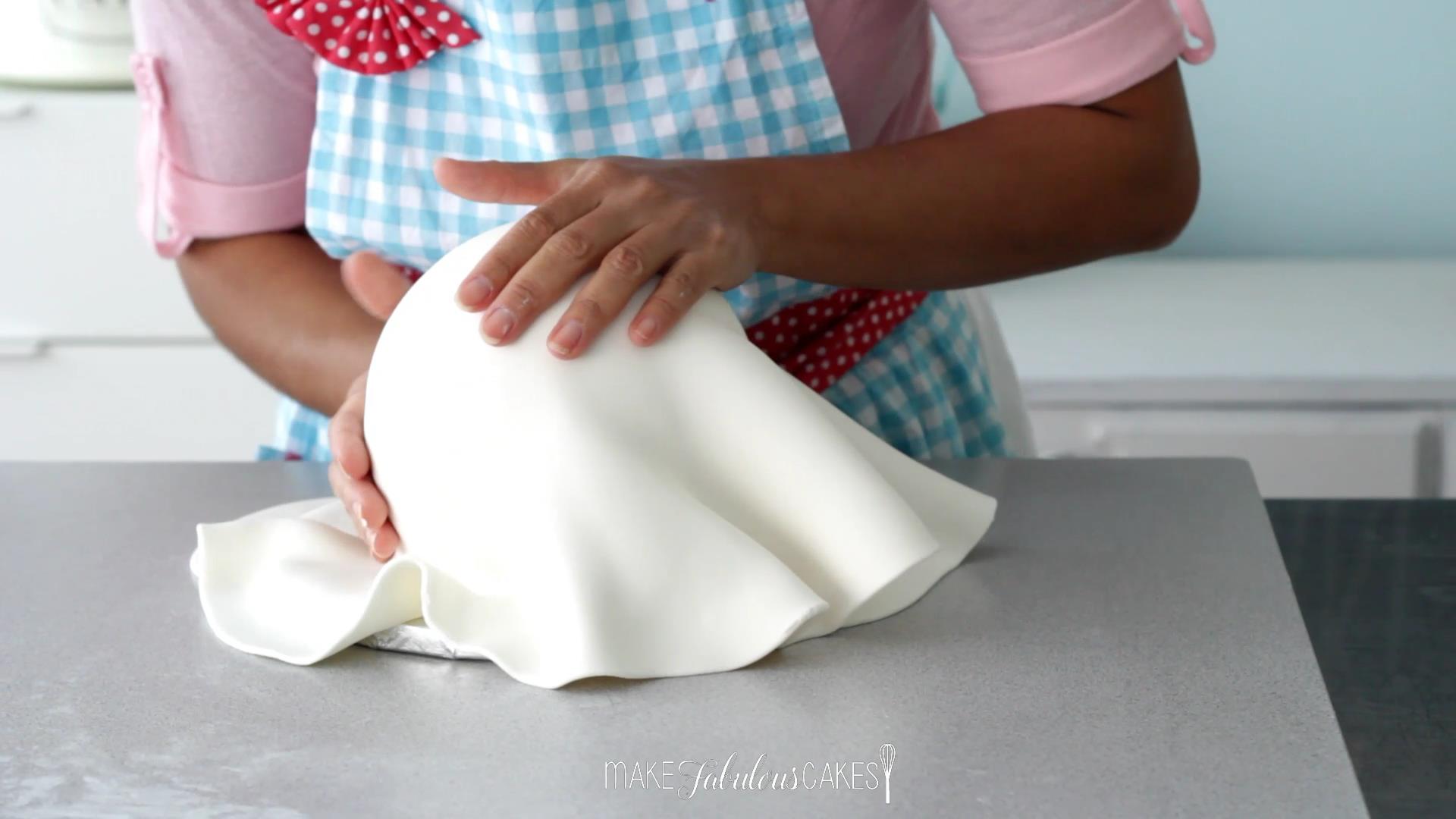 smoothing the fondant on the ball cake with hands