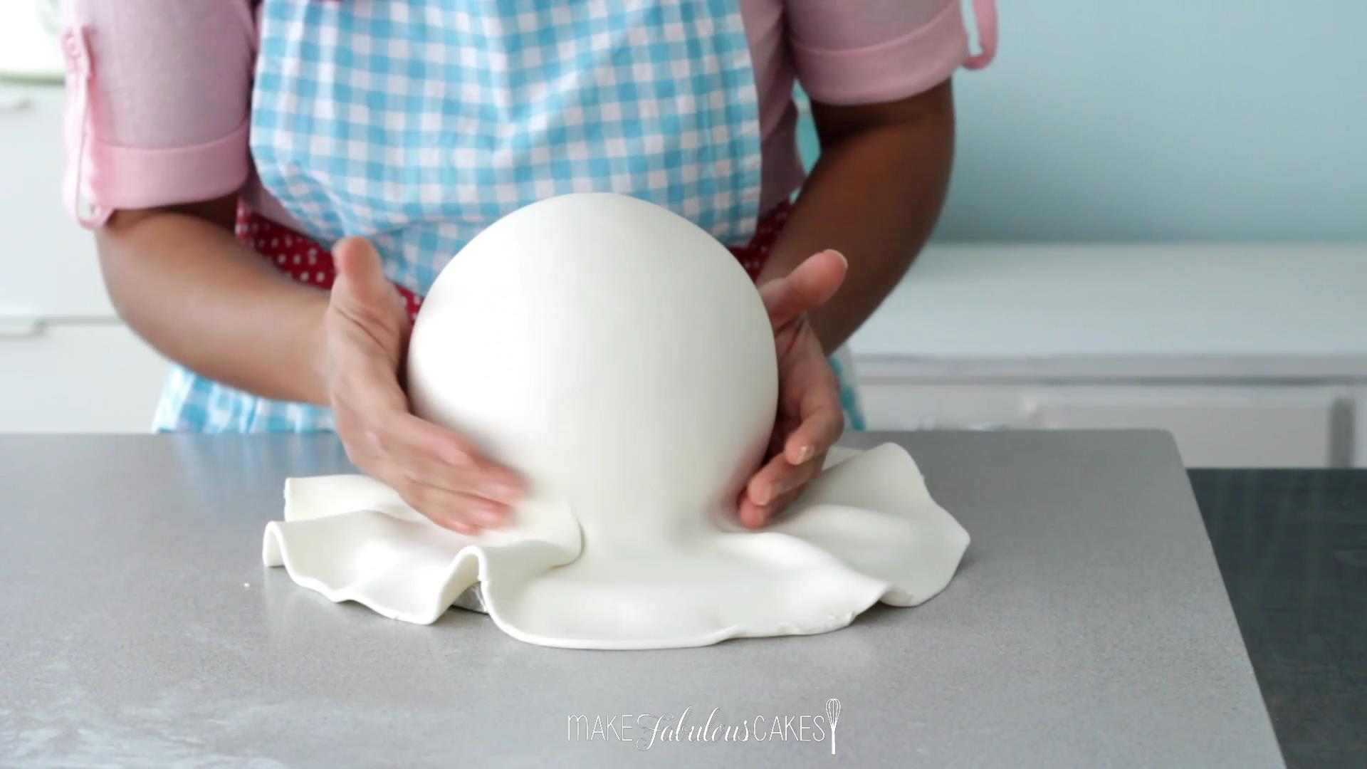 smoothing the fondant on the ball cake with hands