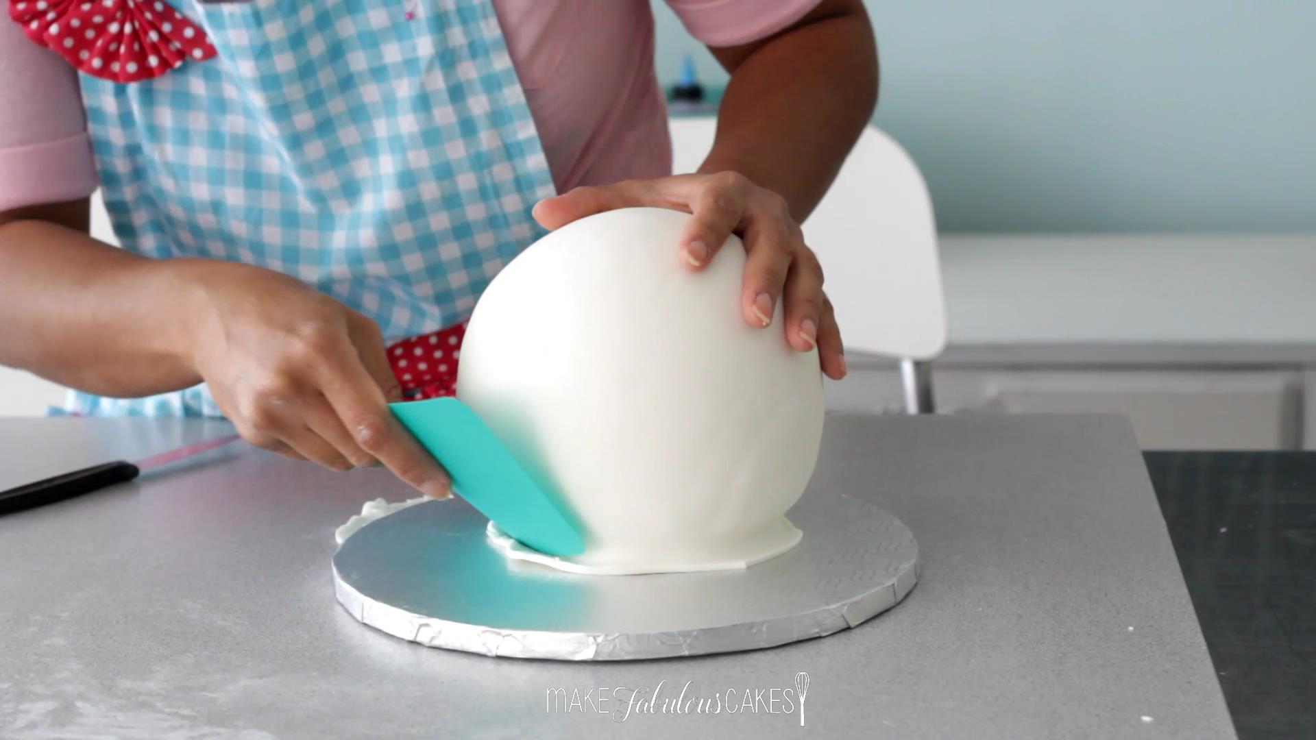 cutting excess fondant from the ball cake